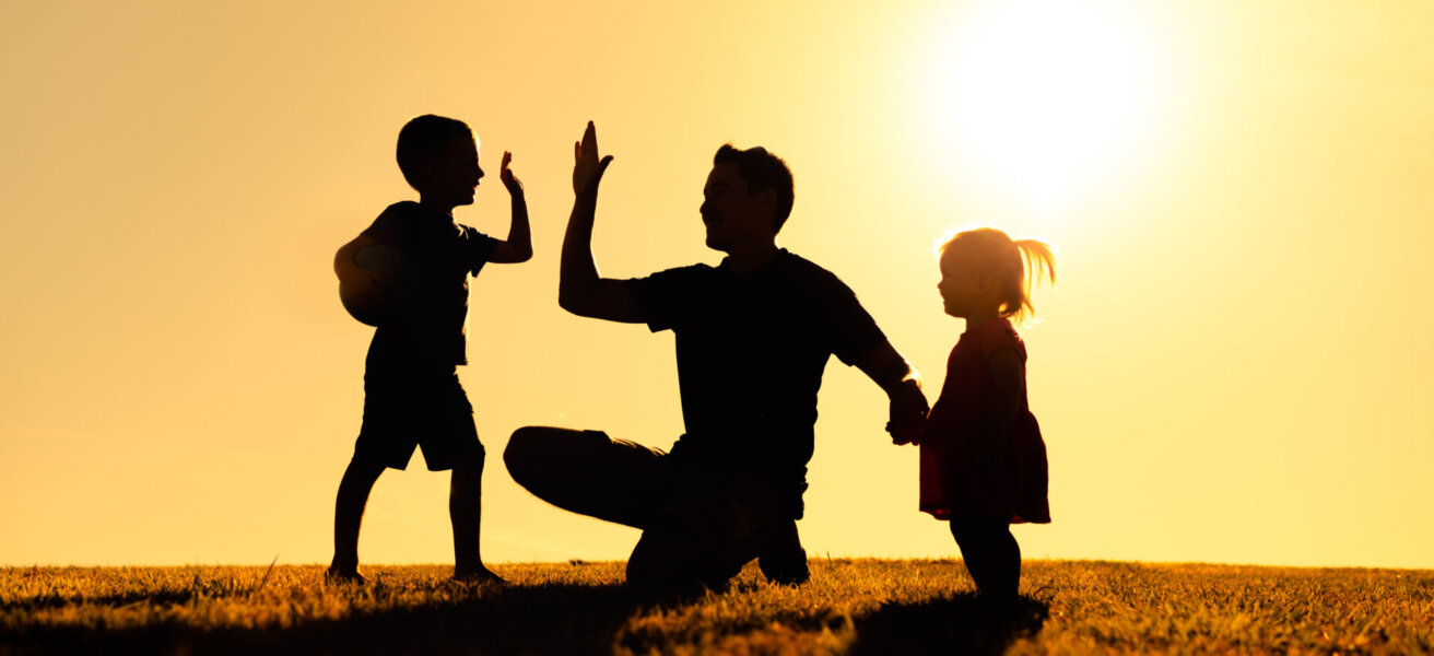 Father interacting playing outdoors with his children giving high five. Parenting and fatherhood concept.
