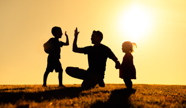 Father interacting playing outdoors with his children giving high five. Parenting and fatherhood concept.