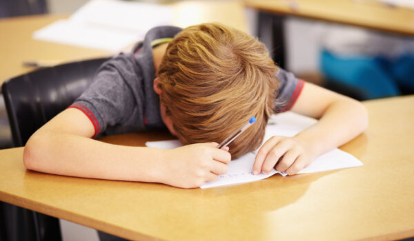 Sleeping, bored and tired with boy in classroom for learning, education and knowledge. Stress, anxiety or confused with male student at desk in school adhd for exhausted, autism problem or frustrated