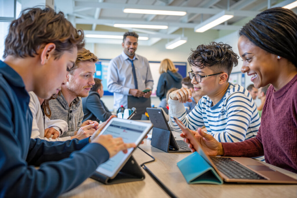 High school students using digital tablets in with teacher