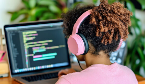 Teenage girl sits at laptop and coding. Black teen girl uses AI powered tool, interactive lessons. Online education, technology, artificial intelligence, science concept