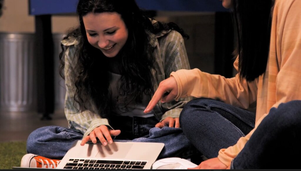 Emiko Pointing at Student Laptop Smiling
