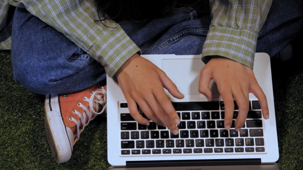 Student Typing on Laptop in gym hands